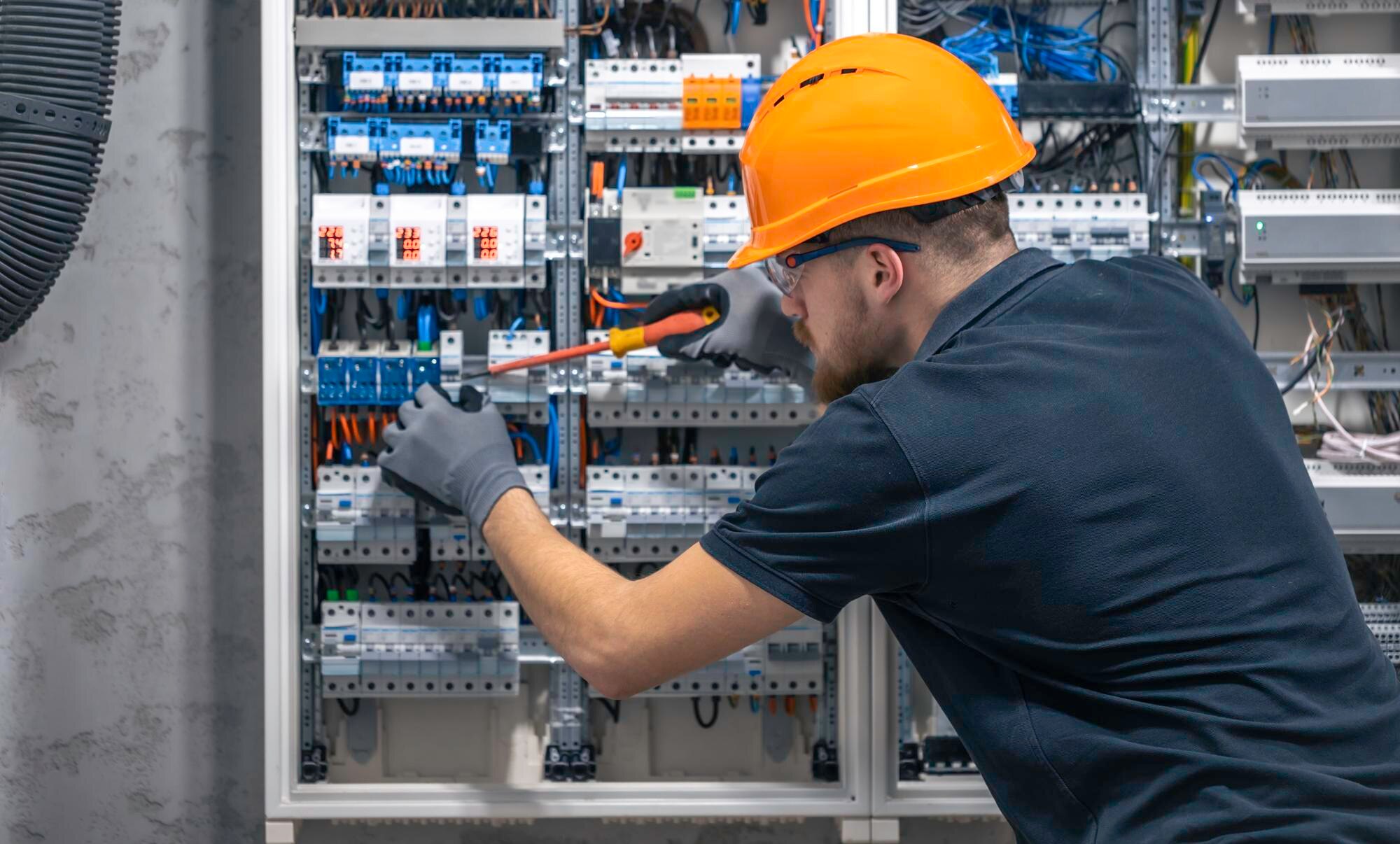 young-adult-electrician-civil-engineer-screwing-equipment-into-fuse-box_169016-52904